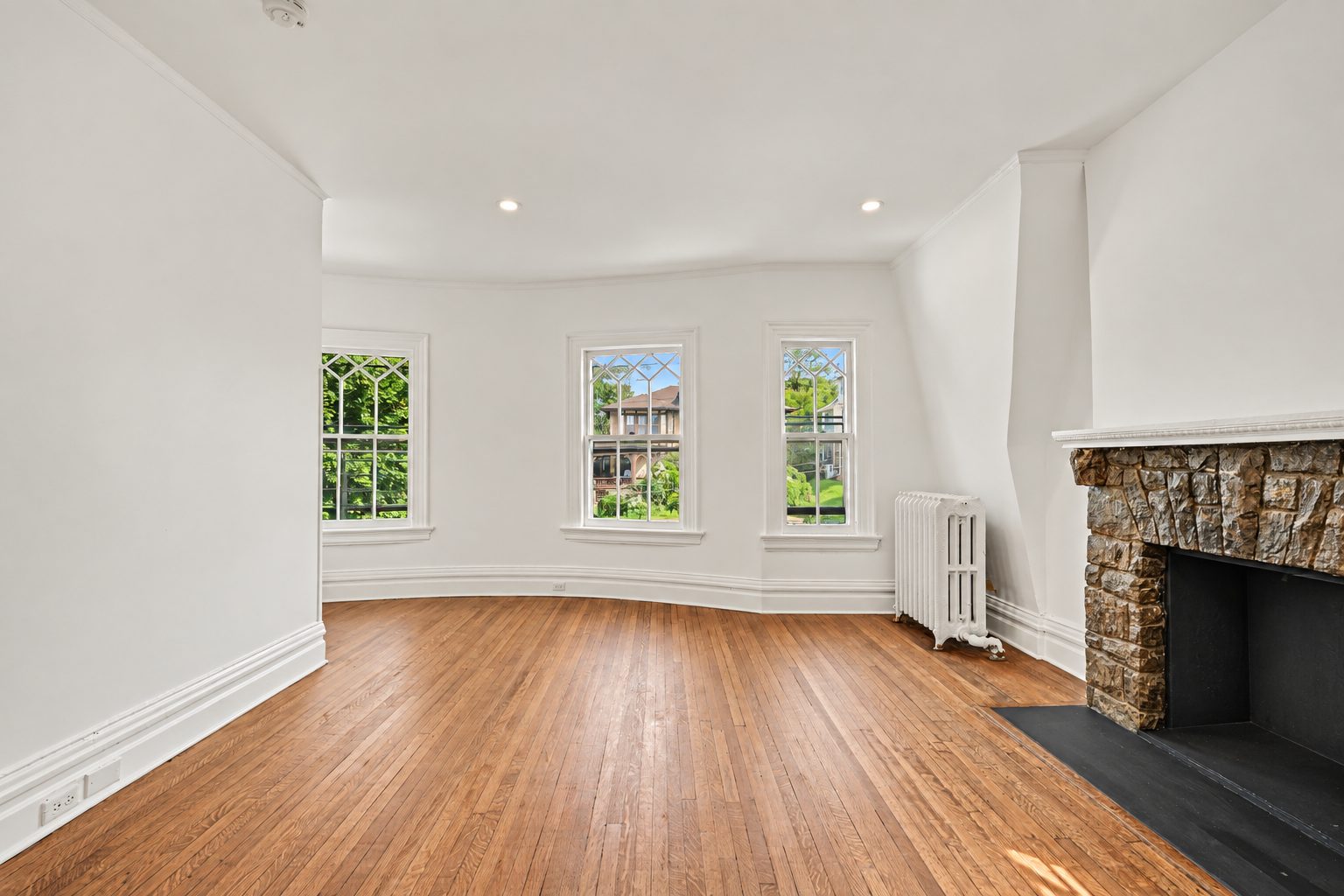 A bedroom with a stone fireplace and a bay of windows
