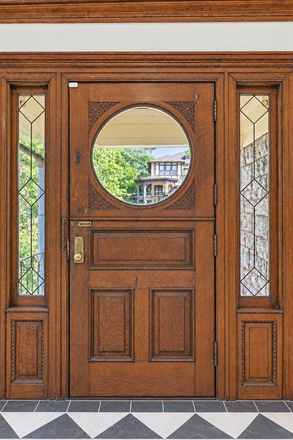 The oak front door with a circular looking glass and leaded-glass side windows